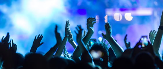 A crowd lifts up their hands at an evening concert