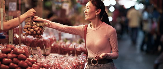 A woman buying fruit at a market stand