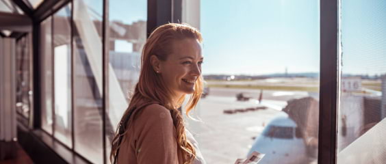 A woman smiles at the airport gate before boarding her plane